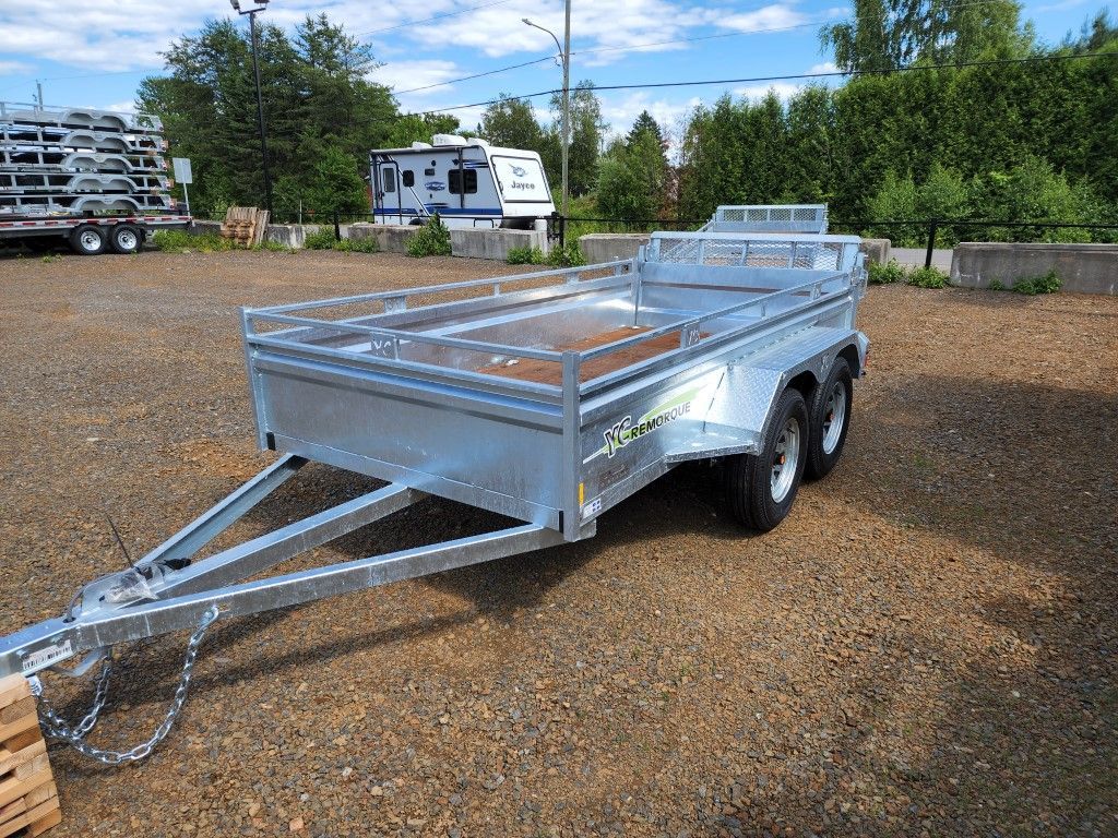 Une remorque est garée sur un terrain en gravier avec un camping-car en arrière-plan.