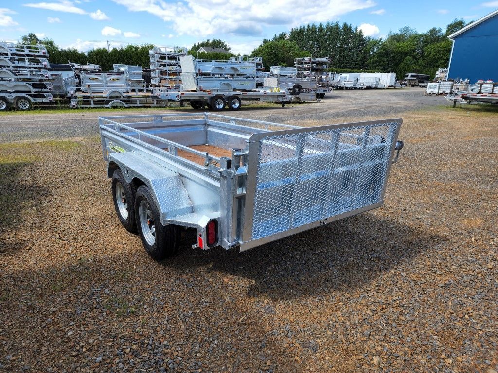 Une remorque est garée sur un terrain en gravier devant un bâtiment.