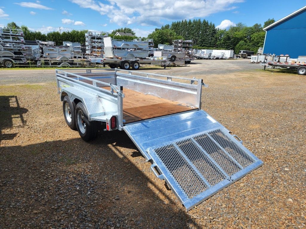 Une remorque est garée sur un terrain en gravier devant un bâtiment.