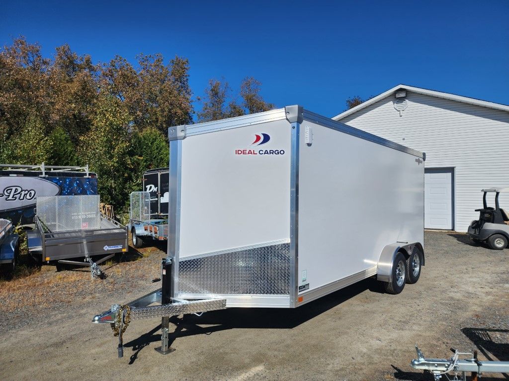 Remorque cargo fermée blanche avec une plaque avant en diamant, garée à l'extérieur par une journée ensoleillée.