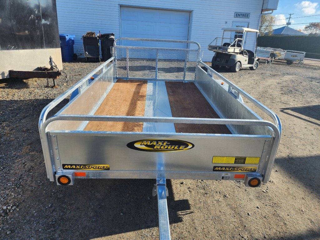 Une remorque est garée devant un garage.