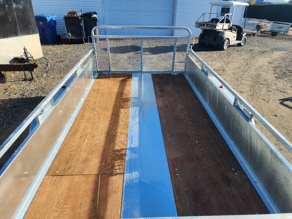 Une remorque avec un plancher en bois est garée sur un parking.