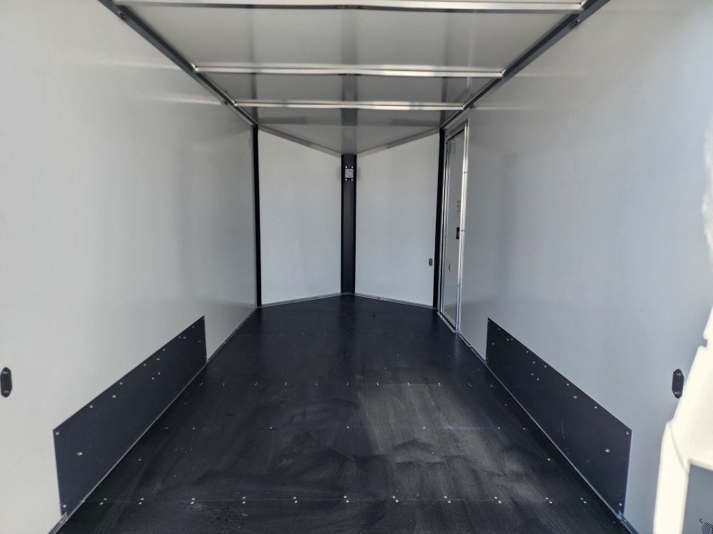 Intérieur d'une remorque blanche vide avec un plancher et des panneaux latéraux noirs.