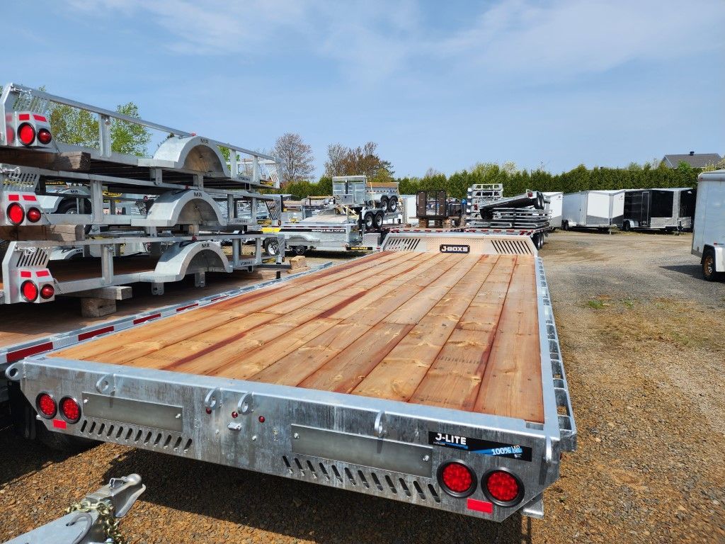 Une remorque à plateau avec un pont en bois est garée dans un parking.