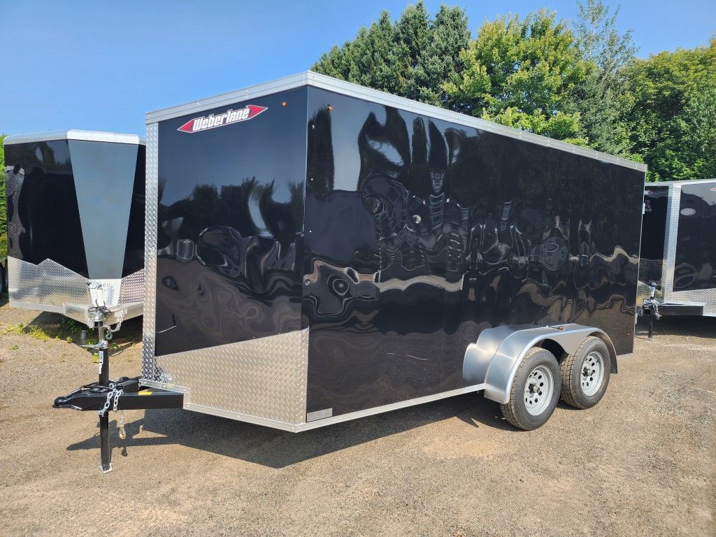Une remorque noire et argentée est garée sur un parking.