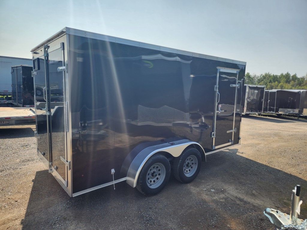 Une remorque noire est garée sur un parking.