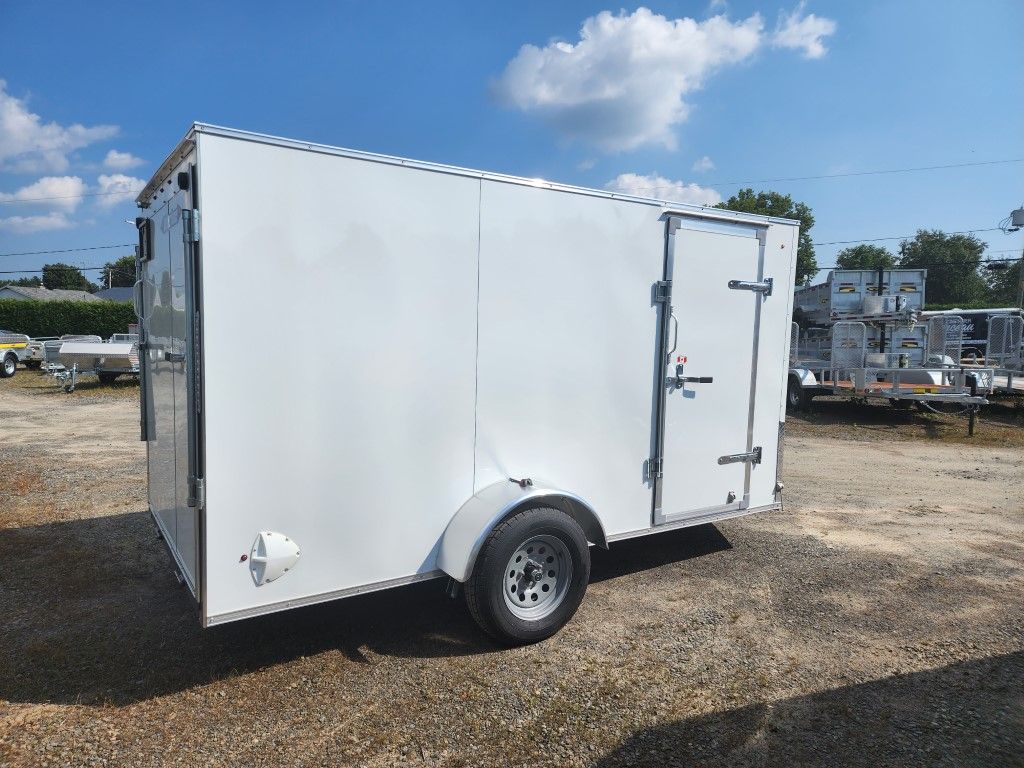 Remorque cargo blanche fermée, avec une seule roue, garée à l'extérieur sur du gravier.