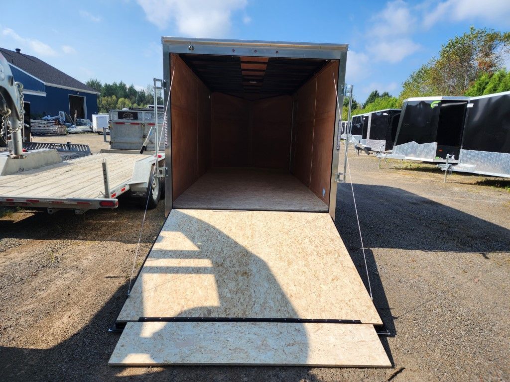 Remorque cargo ouverte avec rampe en bois, garée à l'extérieur par une journée ensoleillée.
