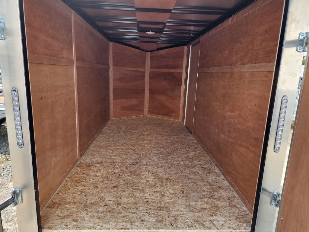 Intérieur de remorque de chargement vide, murs et plancher lambrissés de bois, ossature métallique, porte ouverte.