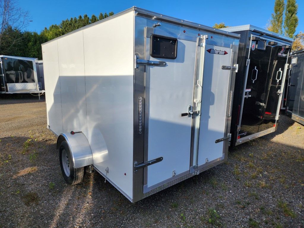 Remorque utilitaire fermée blanche avec portes doubles, stationnée à l'extérieur.