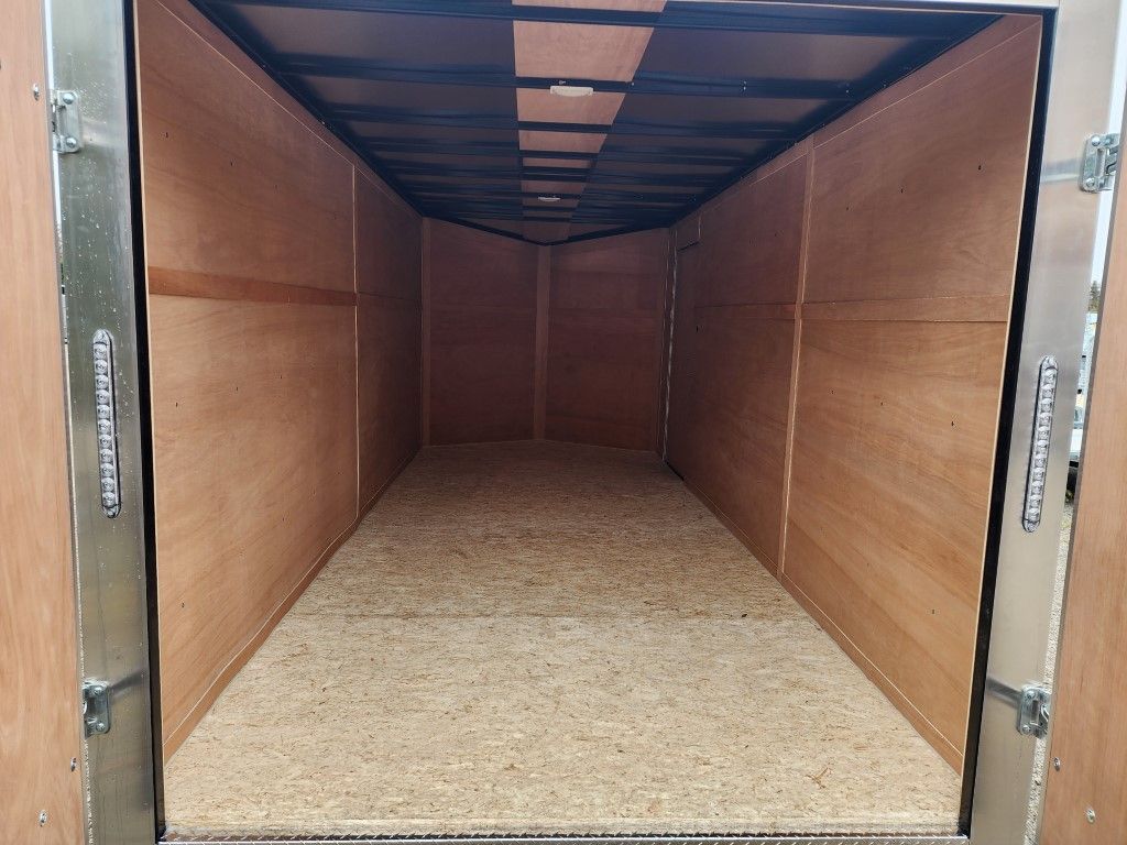 Intérieur d'une remorque fermée et vide, lambris en bois, sol moucheté, cadres de porte en métal.