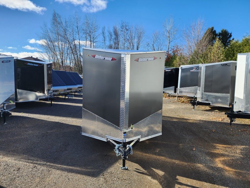 Une remorque argentée est garée sur un parking.