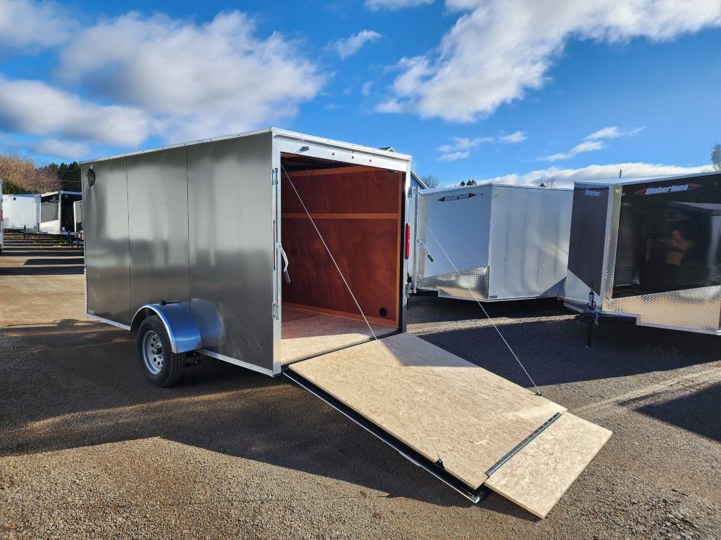 Une remorque avec une rampe est garée dans un parking.