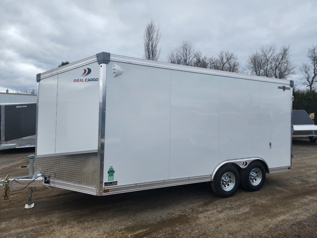 Une remorque blanche est garée sur un terrain en terre.