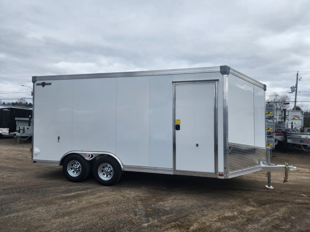 Une remorque blanche est garée sur un terrain en terre.