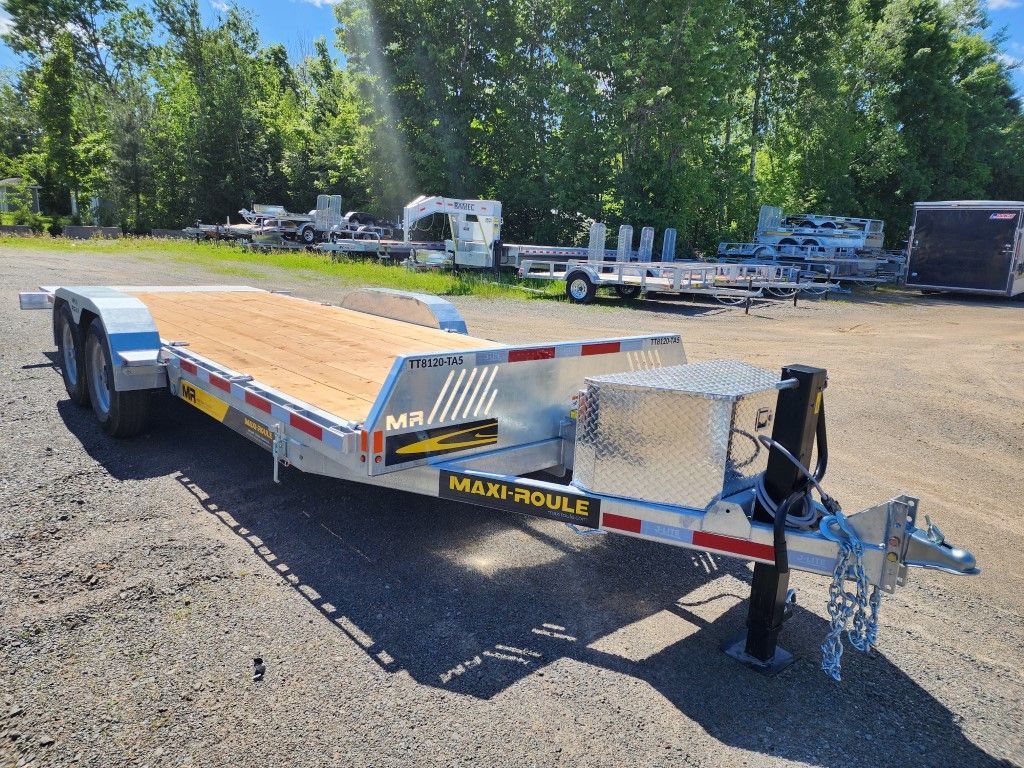 Remorque à plateau avec plancher en bois, stationnée à l'extérieur, à proximité d'autres remorques.