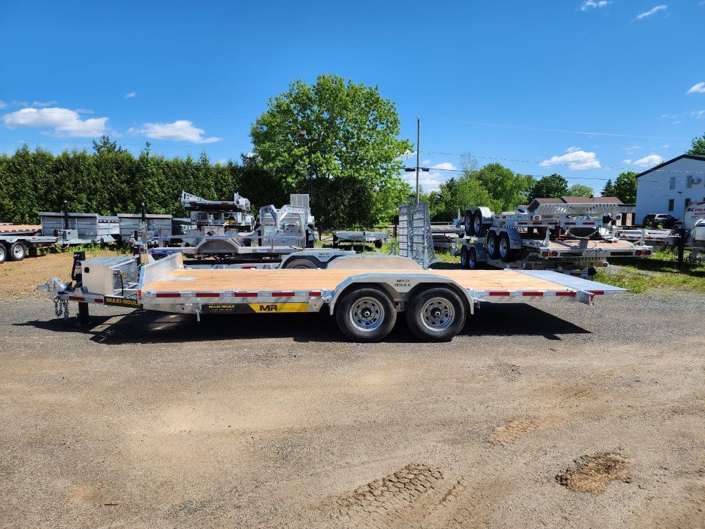 Une remorque à plateau avec un pont en bois est garée à l'extérieur par une journée ensoleillée.