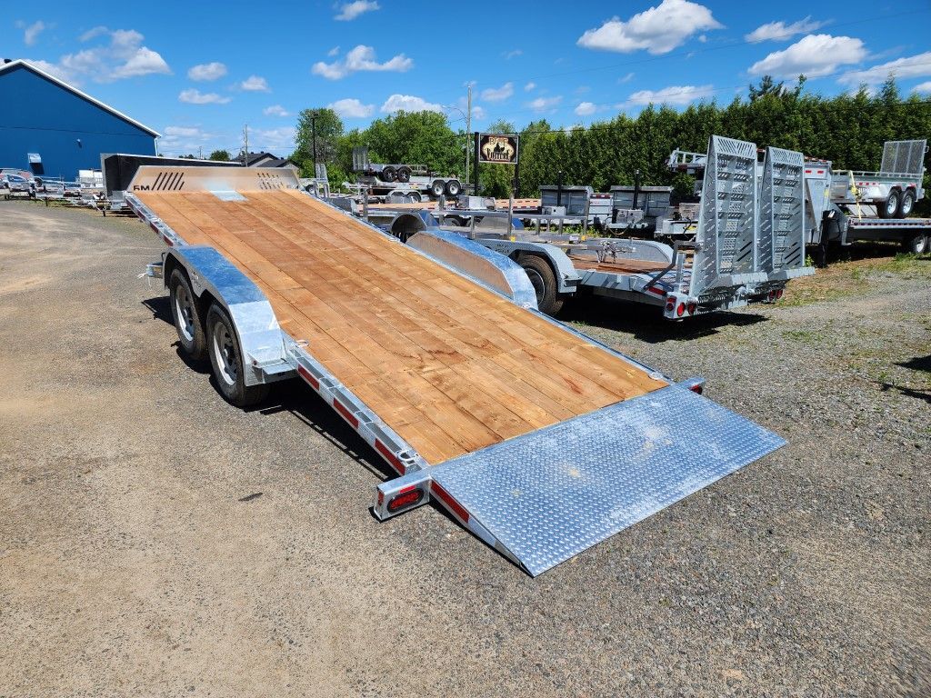 Remorque plateau longue avec plancher en bois sur gravier.