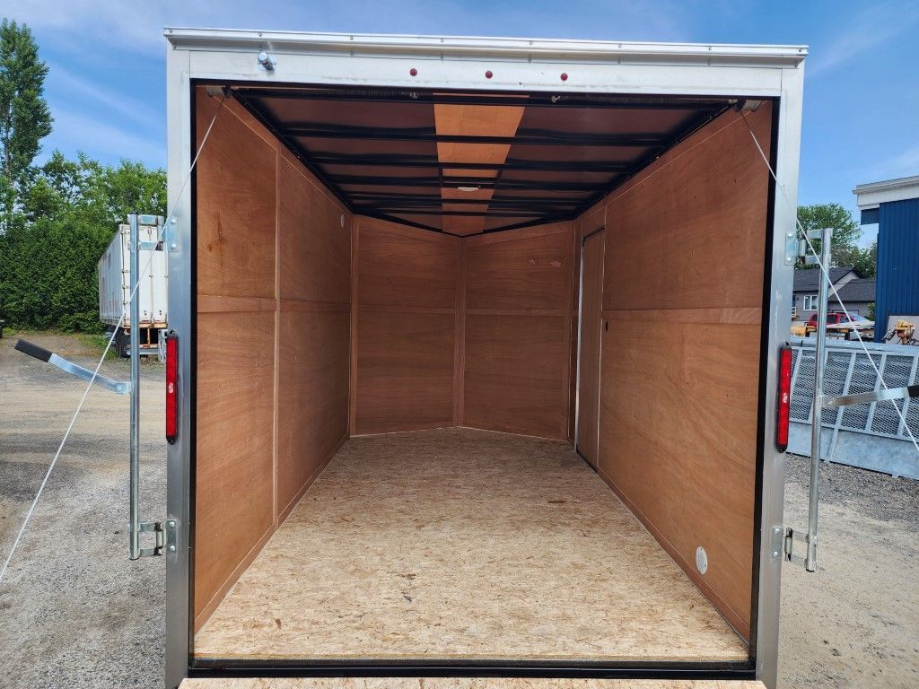 Intérieur de remorque cargo vide, parois et plancher en contreplaqué brun clair, ouvert à l'arrière.