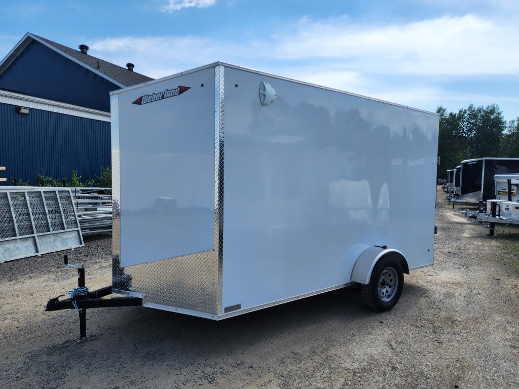 Remorque cargo fermée blanche, garée à l'extérieur sur du gravier.