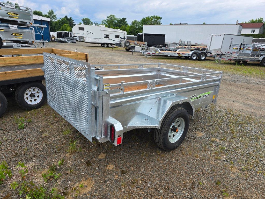 Une remorque est garée sur un terrain en gravier à côté d'un camion.