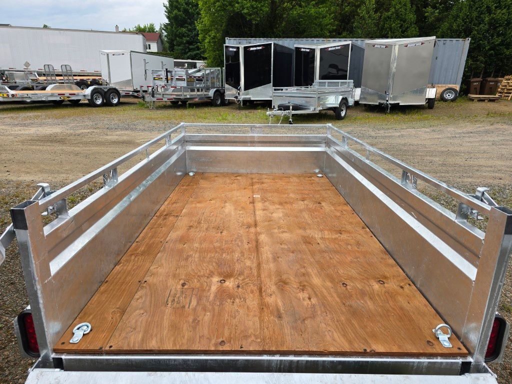 Une remorque avec un plancher en bois est garée sur un parking.