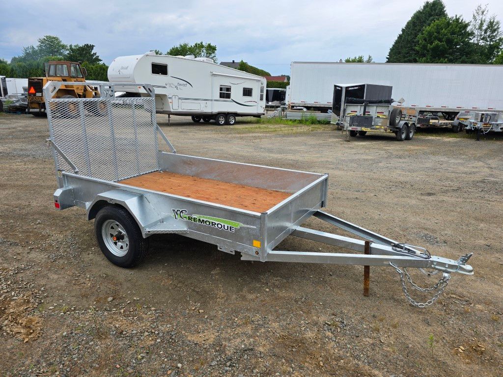 Remorque utilitaire argentée avec un arrière en filet dans un stationnement.