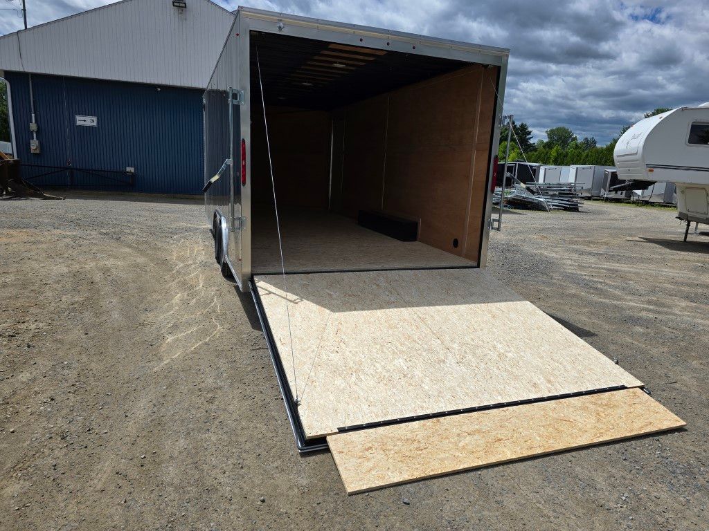 Remorque cargo ouverte avec rampe sur gravier.