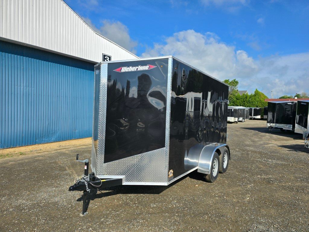 Une remorque noire et argentée est garée devant un bâtiment.