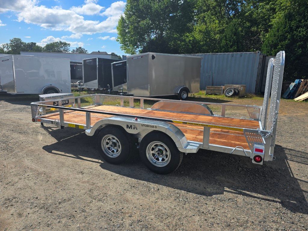 Une remorque avec une terrasse en bois est garée sur un terrain en terre.