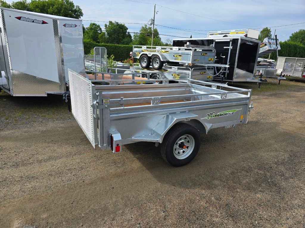 Remorque utilitaire argentée exposée dans un terrain en gravier, avec d'autres remorques en arrière-plan.