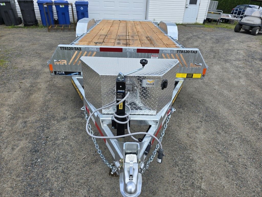 Une remorque avec un pont en bois est garée dans un parking.