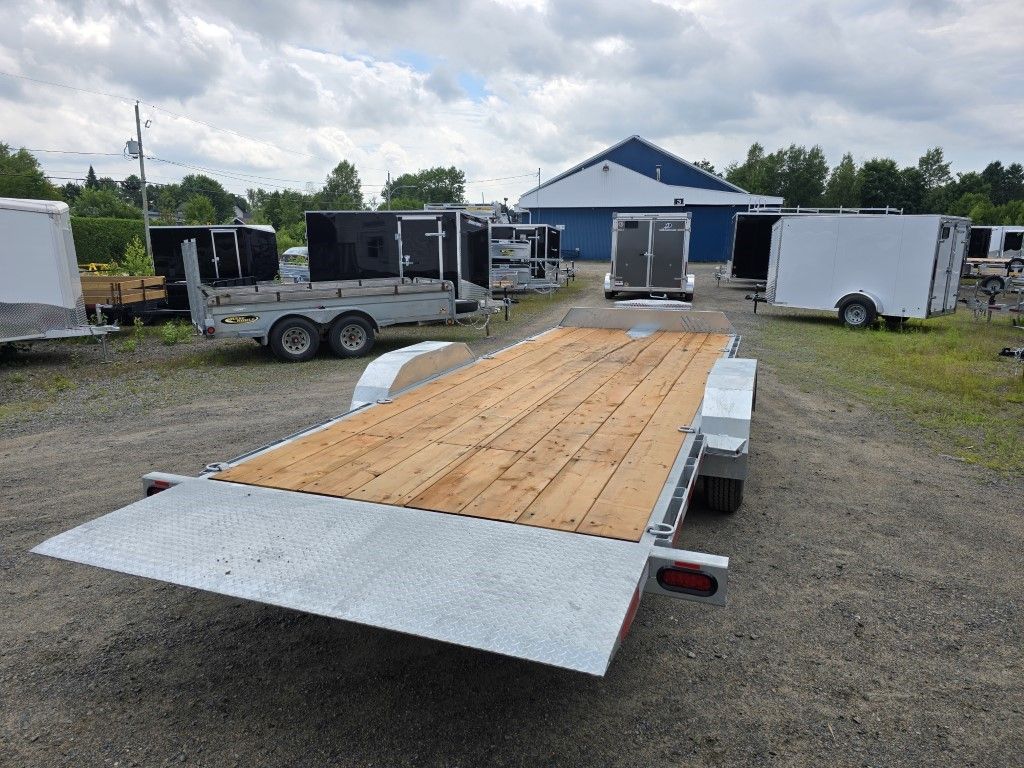 Une remorque avec une terrasse en bois est garée sur un terrain.