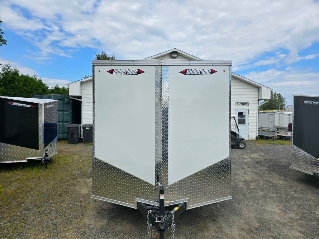 Une remorque blanche est garée devant un bâtiment.