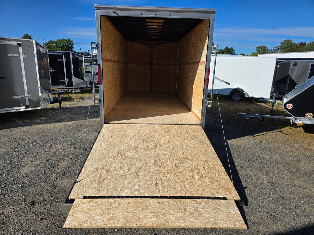 Remorque cargo ouverte avec rampe en bois, garée à l'extérieur par une journée ensoleillée.