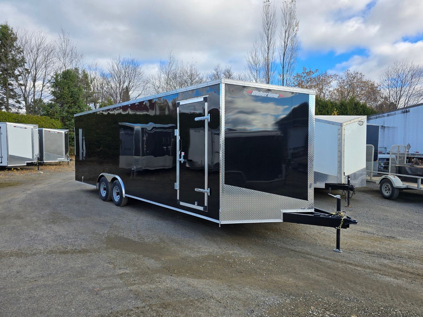 Une remorque noire et argentée est garée sur un parking.
