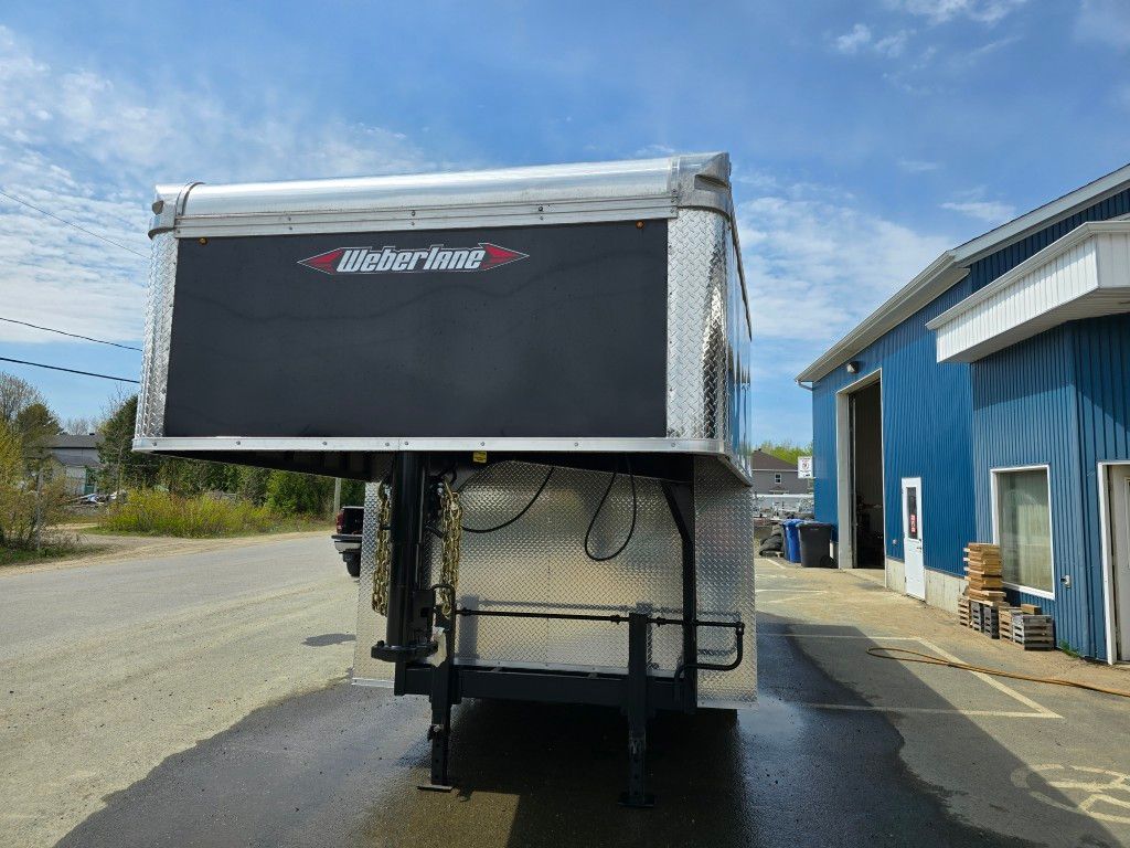 Une remorque noire et argentée est garée sur le bord de la route.