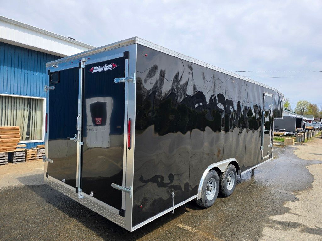 Une remorque noire est garée sur un parking devant un immeuble.