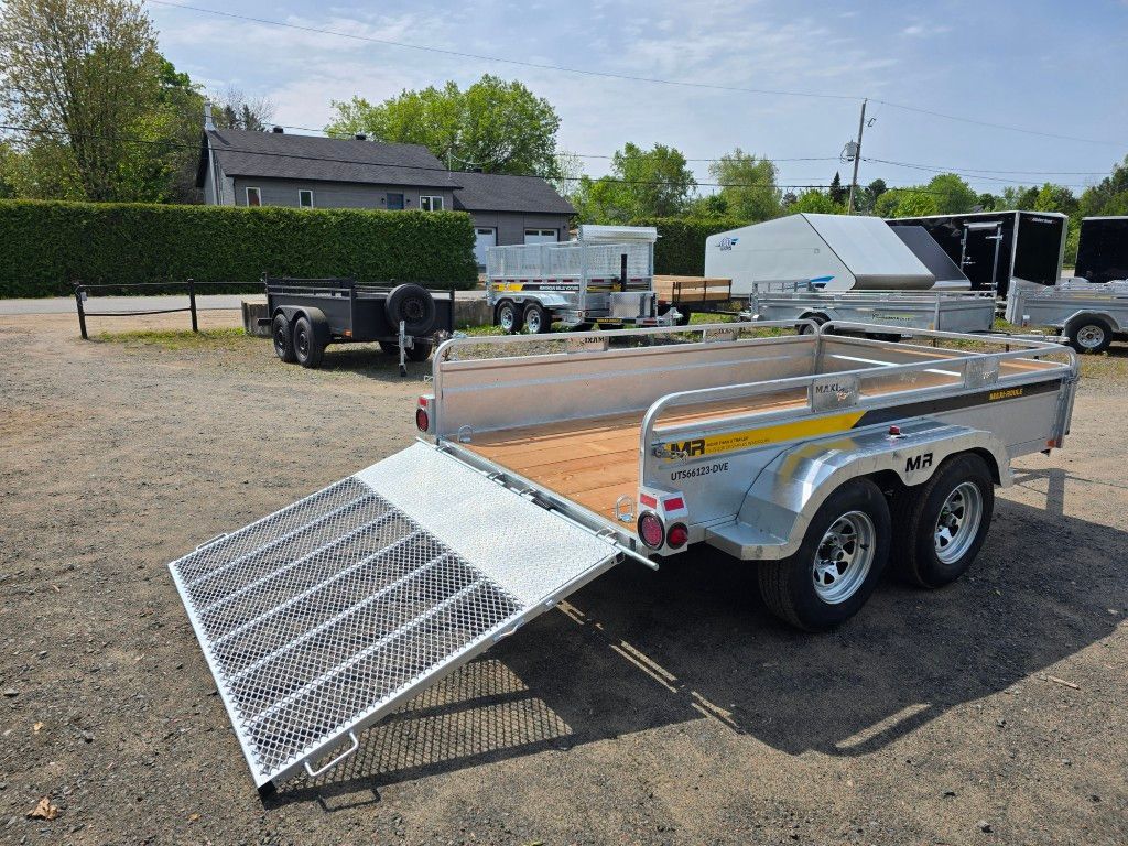 Une remorque avec une rampe est garée dans un parking.