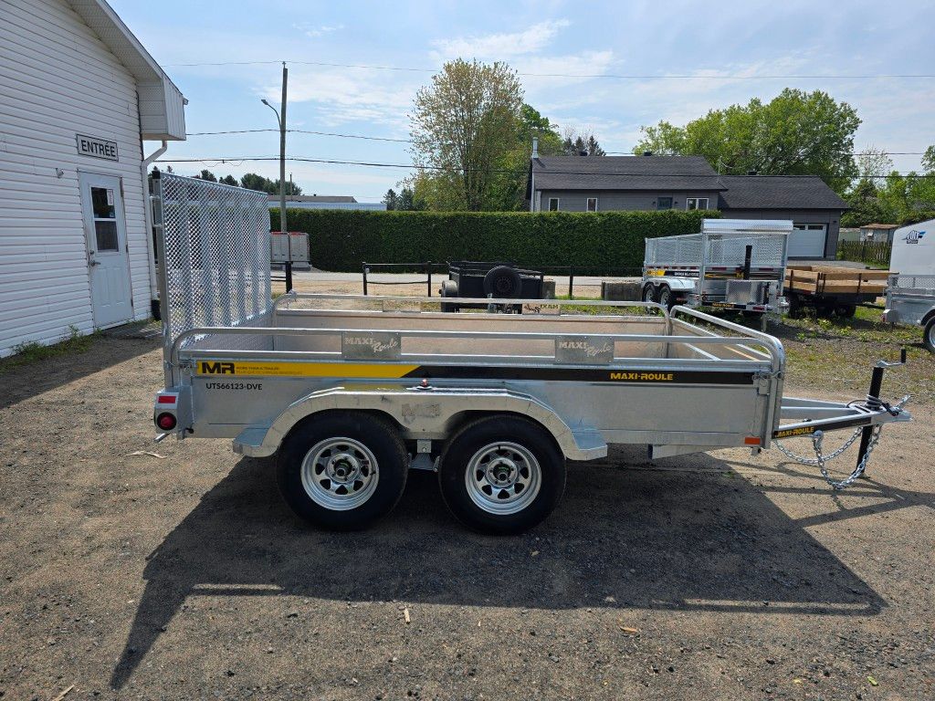 Une remorque est garée sur un terrain en gravier devant un bâtiment.