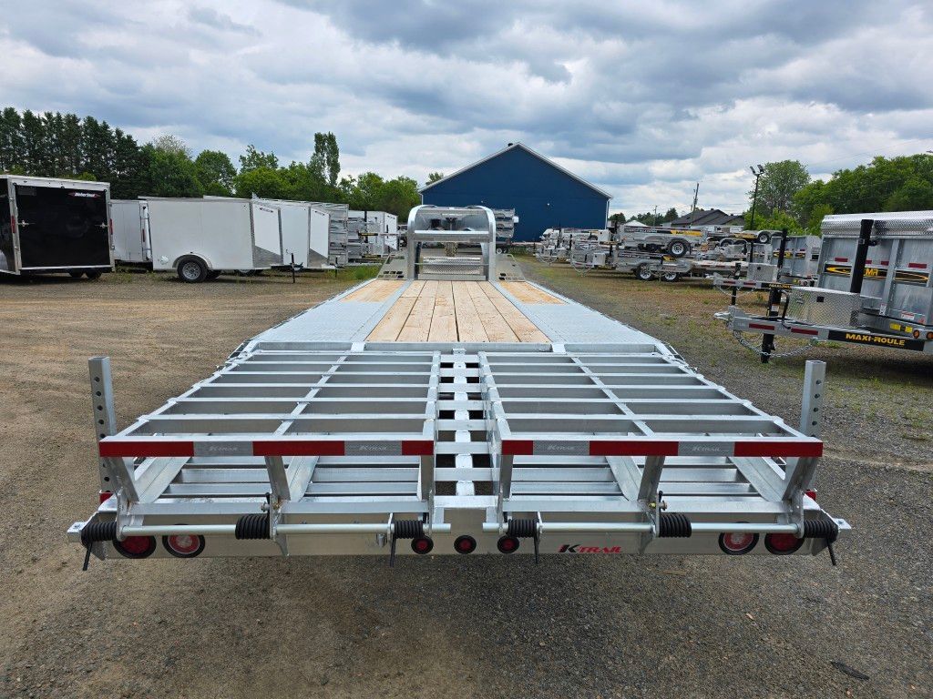 Une remorque est garée sur un parking avec un bâtiment bleu en arrière-plan.