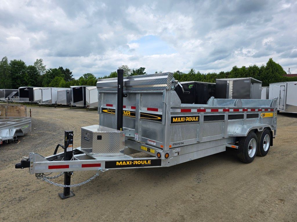 Remorque à benne argentée sur terrain en gravier, sous un ciel nuageux.