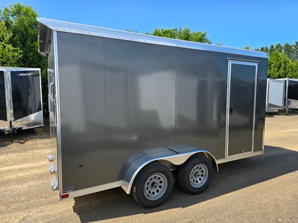 Remorque cargo grise à deux roues, debout à l'extérieur par une journée ensoleillée.