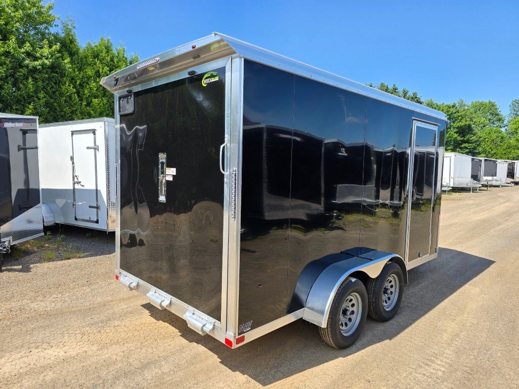 Remorque cargo fermée noire avec garniture argentée, garée sur du gravier.