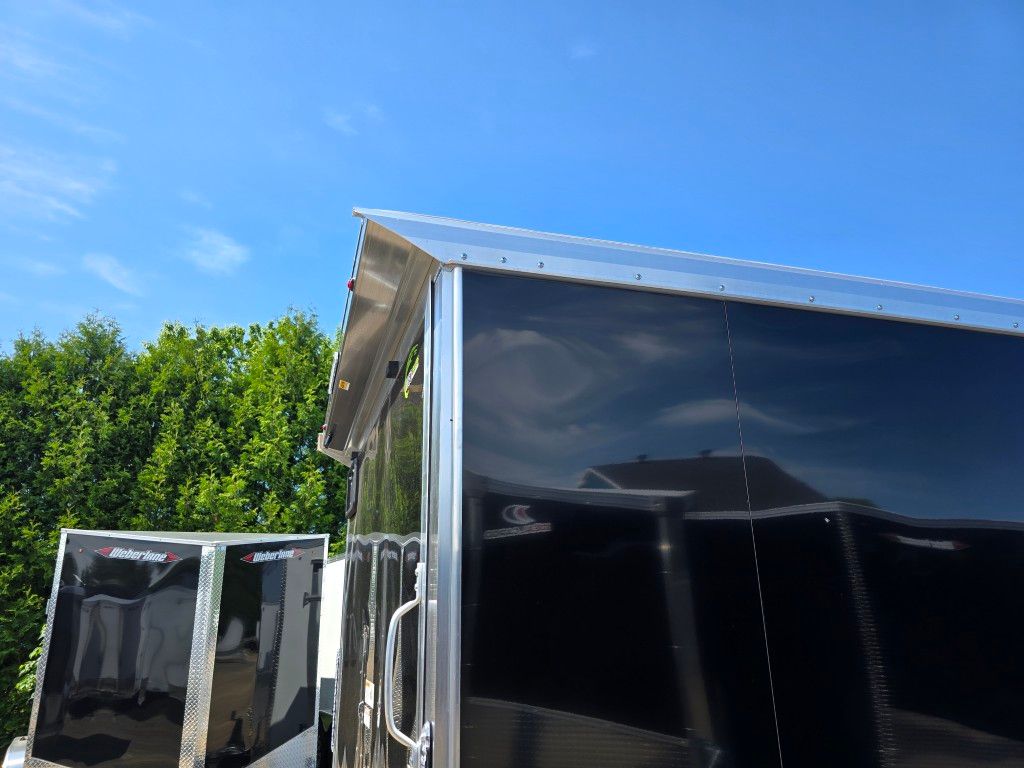 Remorque fermée noire avec garniture en métal brillant sous un ciel bleu.