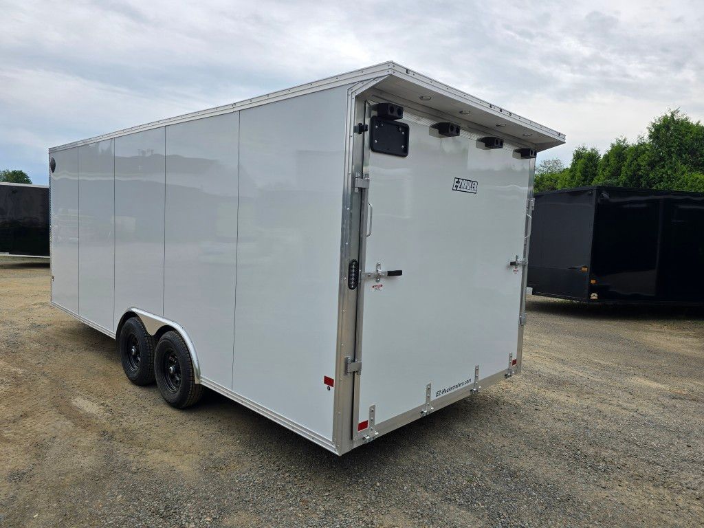 Une remorque blanche est garée sur un terrain en gravier.