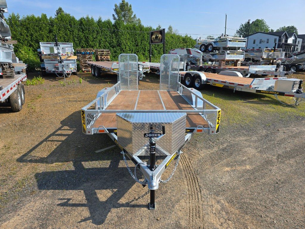Remorque utilitaire argentée avec plate-forme en bois sur terrain en gravier.