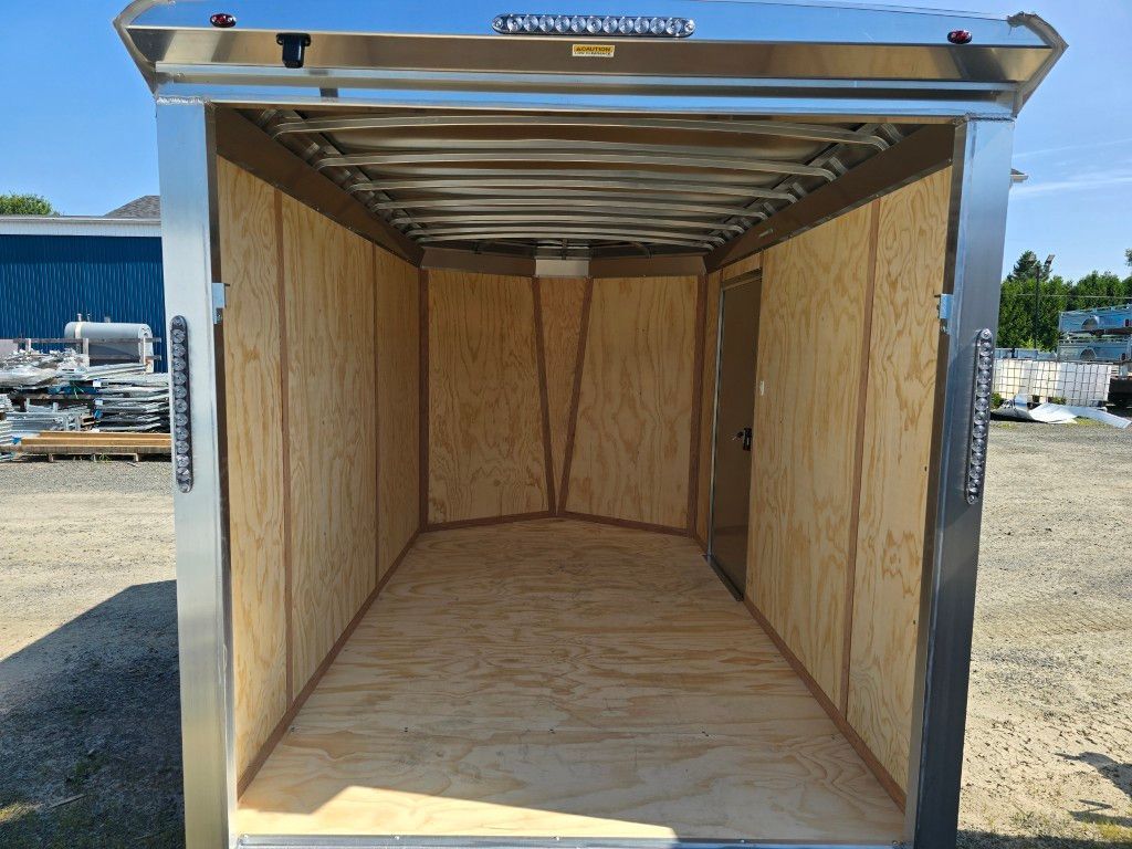 Intérieur de remorque de chargement vide avec parois et plancher en contreplaqué, cadre en acier inoxydable.