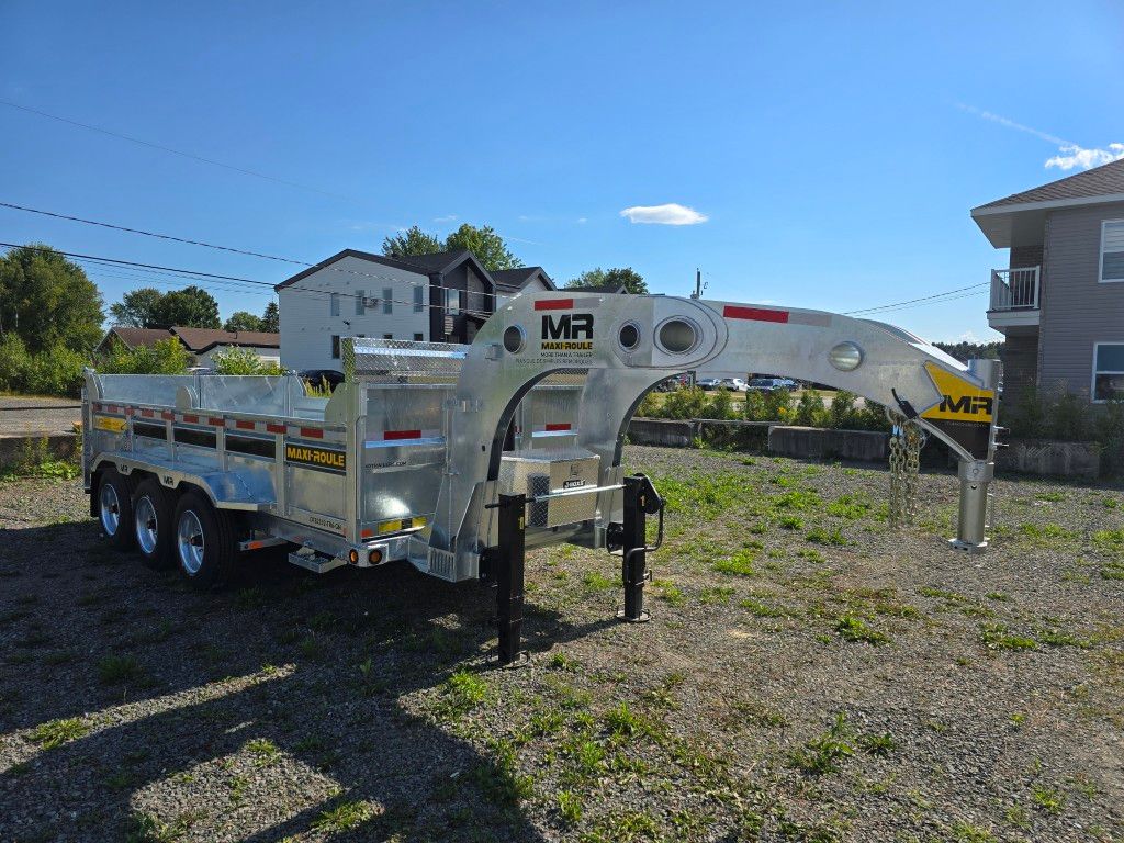 Remorque à plateau argentée et jaune avec un attelage à col de cygne dans un terrain en gravier par une journée ensoleillée.