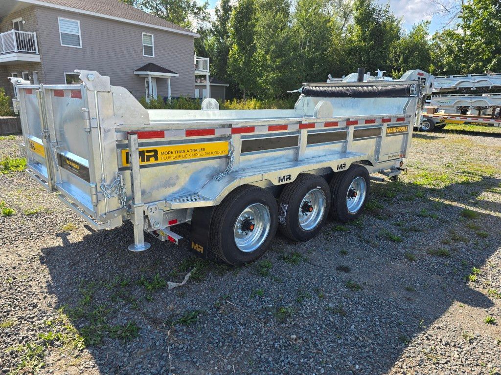 Remorque à benne basculante à trois essieux sur gravier devant un bâtiment. Couleur argent avec touches de jaune.